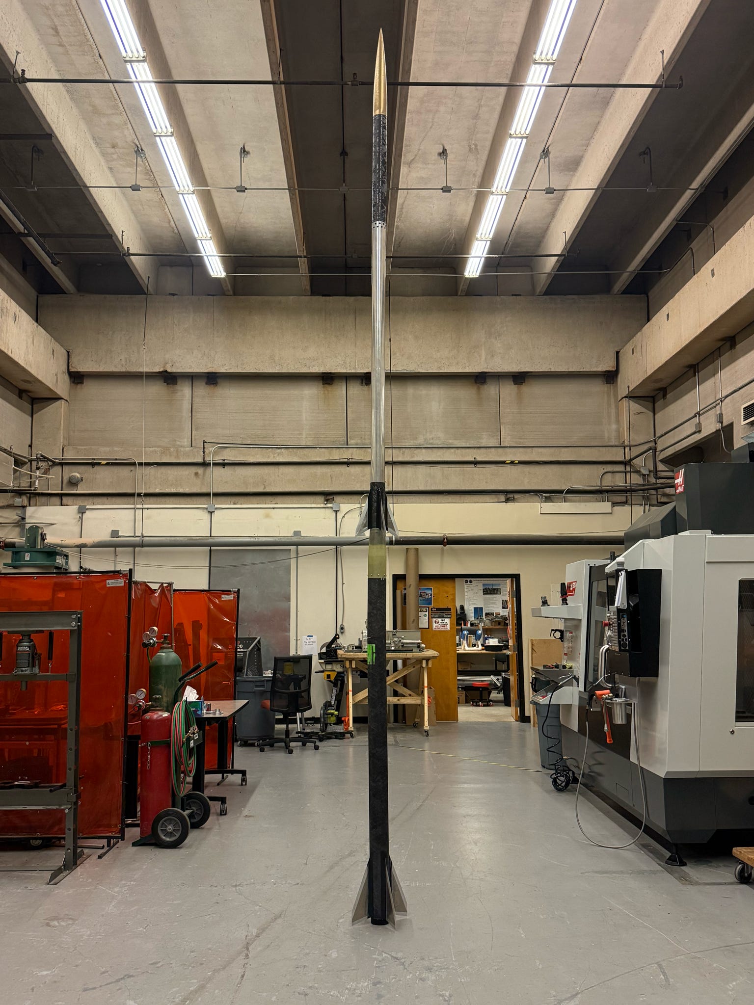 Full rocket standing upright in a workshop.