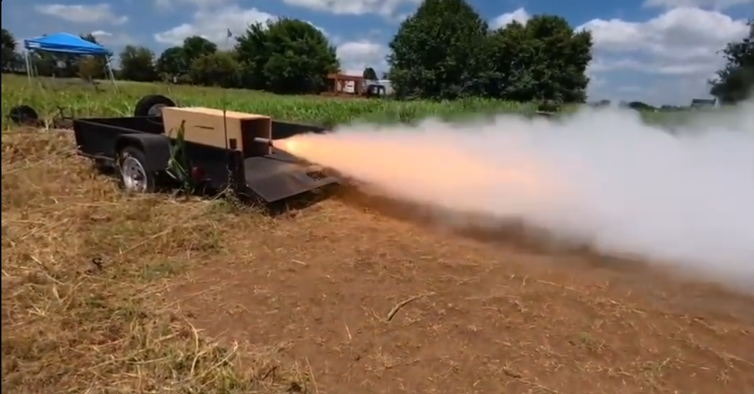N2915 motor test fire with an exhaust plume extending from the test stand.