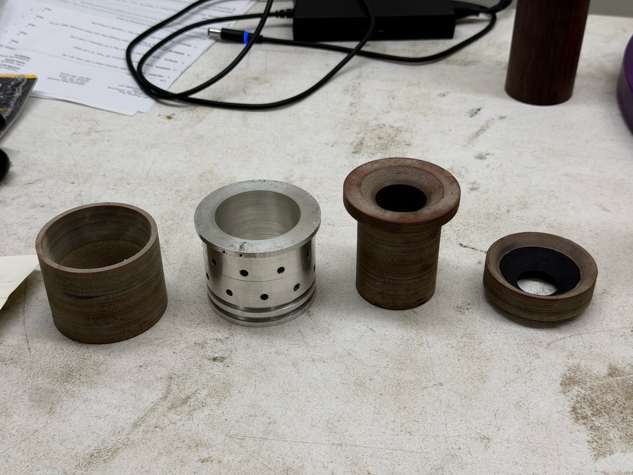 Machined phenolic nozzle hardware and metal component on a workbench.