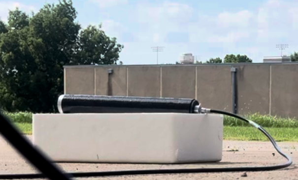 Composite hydro test article connected to a hose outdoors.