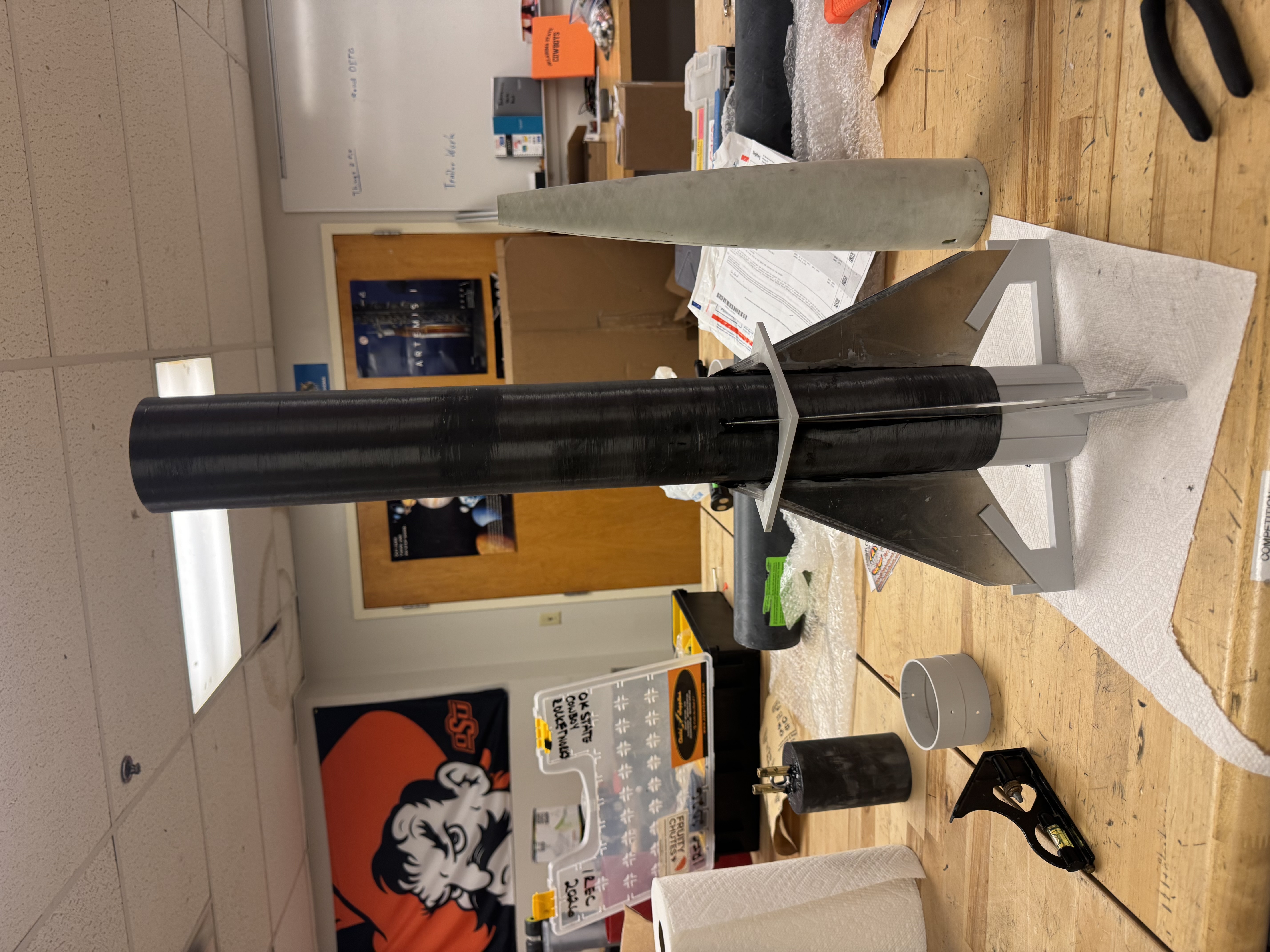 Rocket body and fins supported by printed alignment jigs on a workbench.